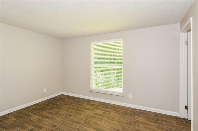 spare room featuring dark hardwood / wood-style flooring and a textured ceiling