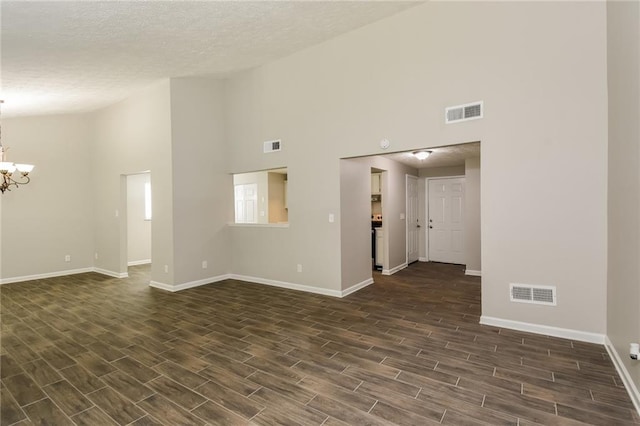 empty room with a textured ceiling, high vaulted ceiling, and a chandelier