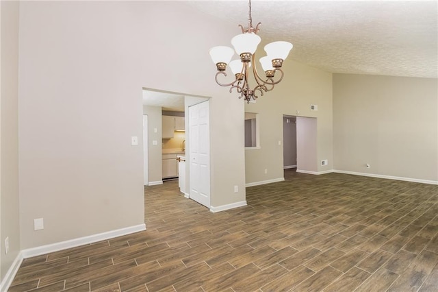 unfurnished room with dark hardwood / wood-style flooring, a notable chandelier, high vaulted ceiling, and a textured ceiling