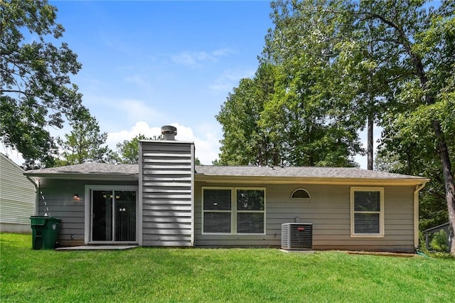 rear view of property with central AC unit and a yard