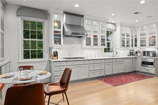 5545 Cross Gate Ct, Atlanta, GA 30327 - kitchen featuring light wood-style floors, wall chimney range hood, decorative backsplash, light countertops, and recessed lighting