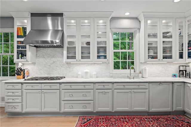 5545 Cross Gate Ct, Atlanta, GA 30327 - kitchen with wall chimney exhaust hood, stainless steel gas stovetop, a sink, backsplash, and glass insert cabinets