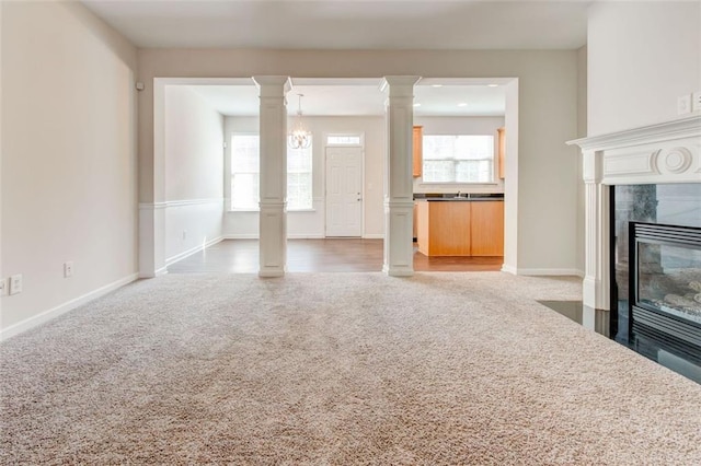 unfurnished living room with ornate columns, carpet floors, and a high end fireplace