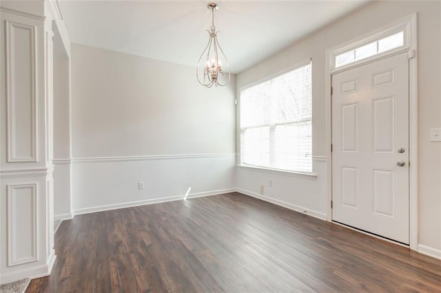 entryway with dark wood-type flooring and a chandelier