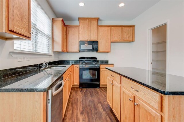 kitchen with sink, light brown cabinetry, dark stone countertops, black appliances, and dark hardwood / wood-style flooring