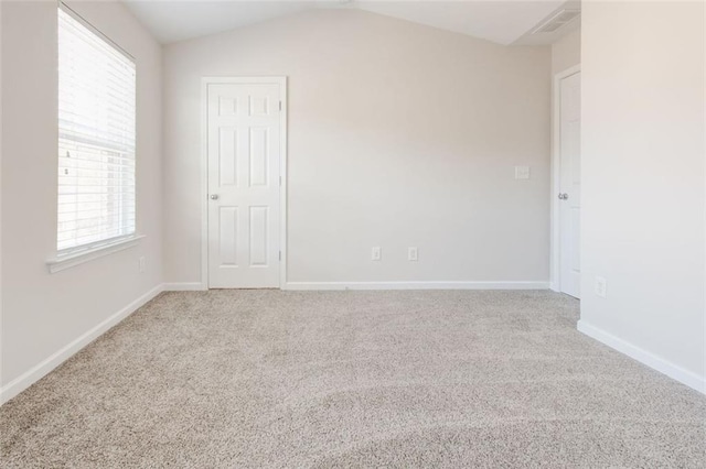 carpeted empty room featuring lofted ceiling