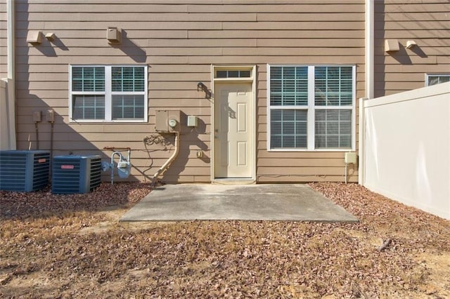 view of exterior entry featuring central AC unit and a patio