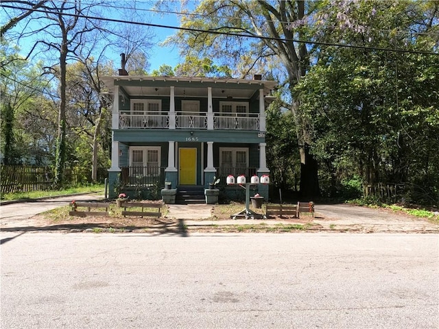 view of front of home with a balcony, covered porch, and french doors