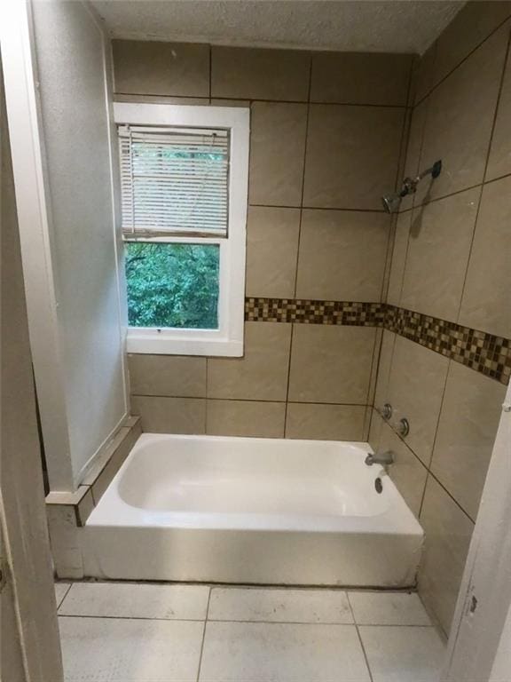 bathroom featuring tile patterned floors, tiled shower / bath, and a textured ceiling