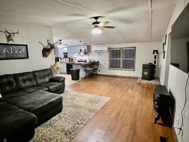 9262 Morrison Rd, Lula, GA 30554 - living area featuring a ceiling fan, light wood finished floors, a wood stove, vaulted ceiling, and a wall mounted AC