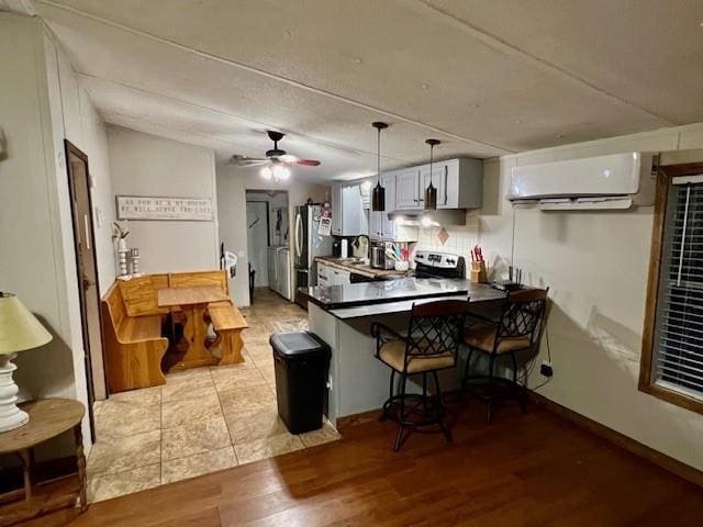 9262 Morrison Rd, Lula, GA 30554 - kitchen with an AC wall unit, a peninsula, light wood finished floors, freestanding refrigerator, and hanging light fixtures