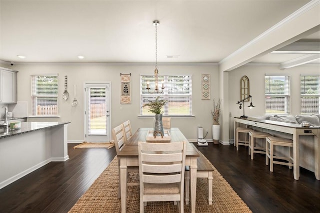 dining room featuring a healthy amount of sunlight, crown molding, dark wood-type flooring, and an inviting chandelier