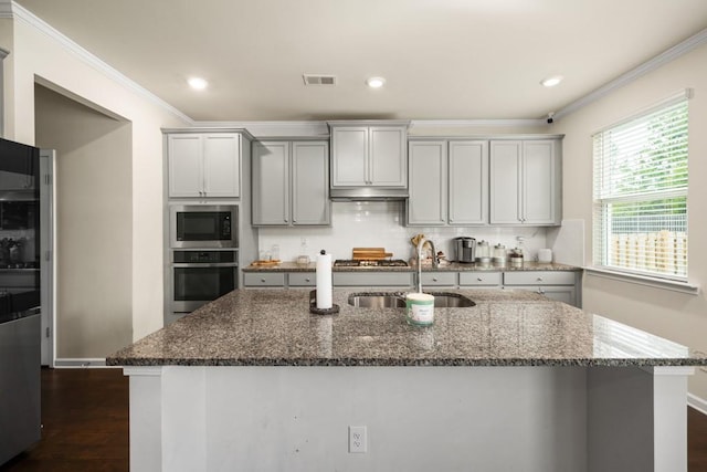 kitchen featuring sink, dark wood-type flooring, dark stone countertops, appliances with stainless steel finishes, and ornamental molding