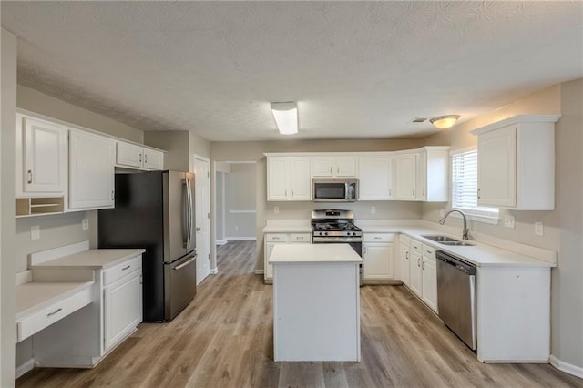 kitchen with white cabinets, light wood-style flooring, a kitchen island, stainless steel appliances, and a sink