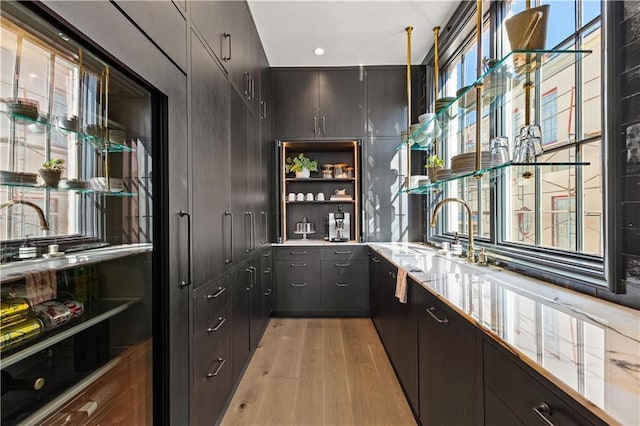 bar featuring dark brown cabinets, sink, and light hardwood / wood-style floors