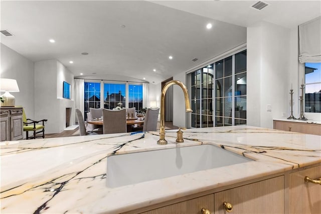 kitchen with lofted ceiling, sink, and light stone countertops