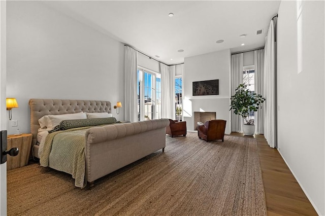 bedroom with dark wood-type flooring, multiple windows, and access to outside