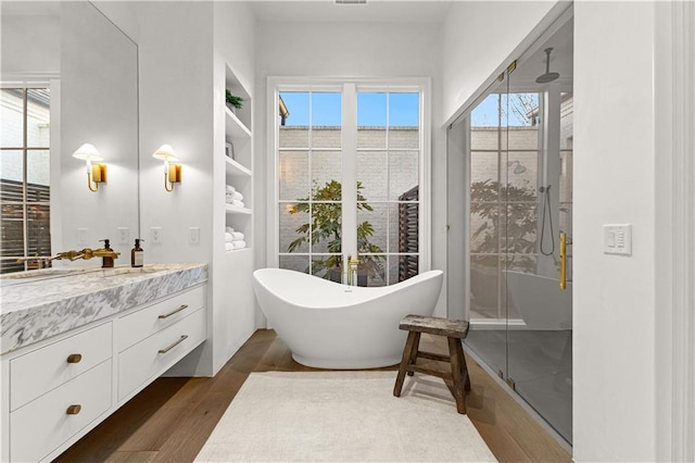 bathroom featuring independent shower and bath, vanity, wood-type flooring, and built in features