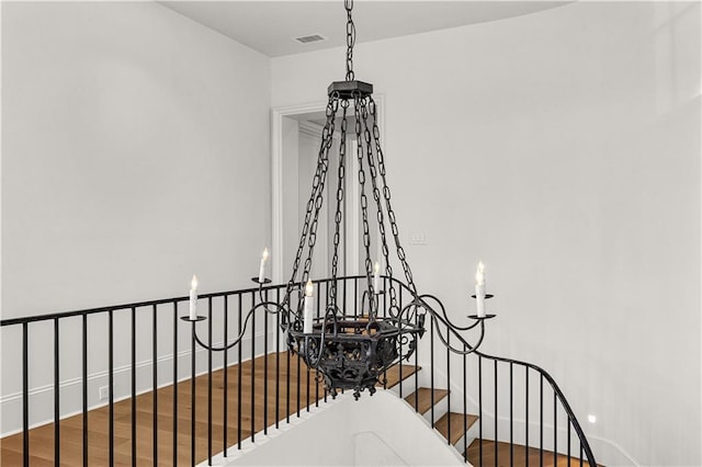 stairs featuring hardwood / wood-style floors and a notable chandelier