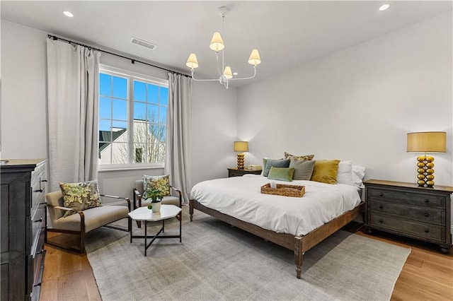 bedroom with an inviting chandelier and light wood-type flooring