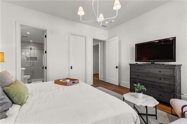 bedroom with ensuite bathroom, an inviting chandelier, and dark hardwood / wood-style flooring