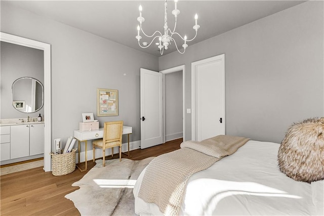 bedroom with an inviting chandelier, sink, hardwood / wood-style flooring, and ensuite bathroom