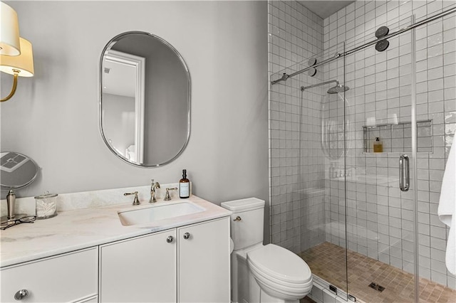 bathroom featuring vanity, a shower with shower door, and toilet