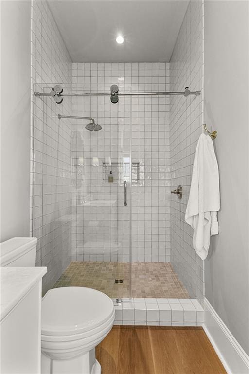 bathroom featuring hardwood / wood-style flooring, toilet, and a shower with shower door