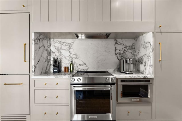 kitchen featuring light stone counters, white cabinetry, stainless steel appliances, and decorative backsplash