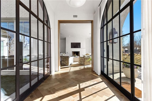 doorway featuring a wealth of natural light, a towering ceiling, parquet floors, and french doors