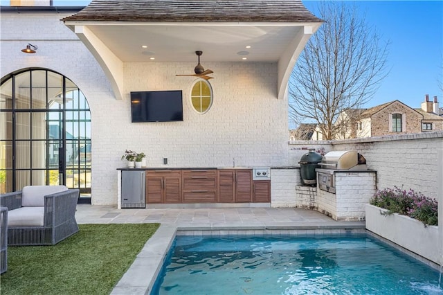 view of pool featuring ceiling fan, grilling area, exterior kitchen, and a patio area