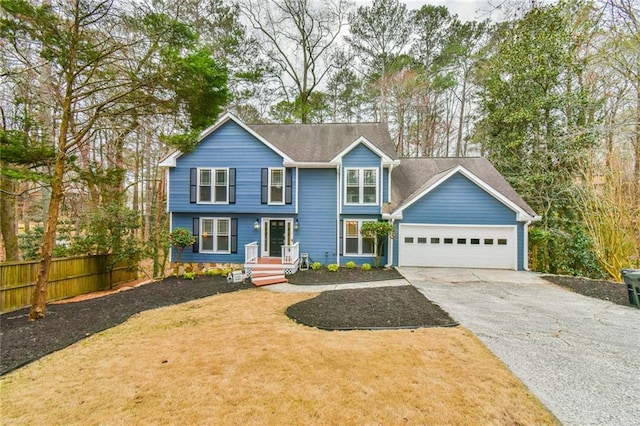 view of front of house featuring a front lawn, fence, driveway, and an attached garage