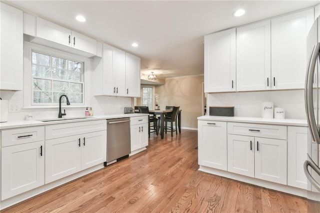 kitchen with light wood-type flooring, white cabinets, a sink, and stainless steel dishwasher