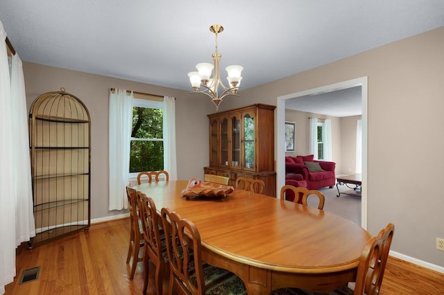 dining area featuring light wood-type flooring and an inviting chandelier