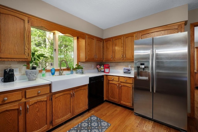 kitchen with dishwasher, light hardwood / wood-style floors, sink, stainless steel refrigerator with ice dispenser, and backsplash