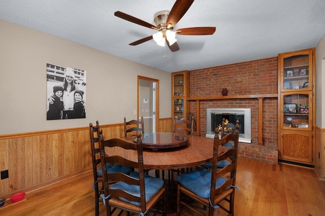 dining room featuring brick wall, a textured ceiling, a fireplace, and hardwood / wood-style floors