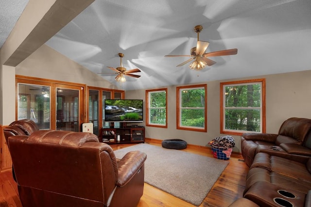 living room with ceiling fan, light hardwood / wood-style floors, and vaulted ceiling