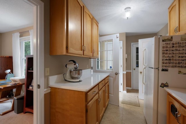 kitchen featuring light tile patterned floors, a textured ceiling, and white fridge