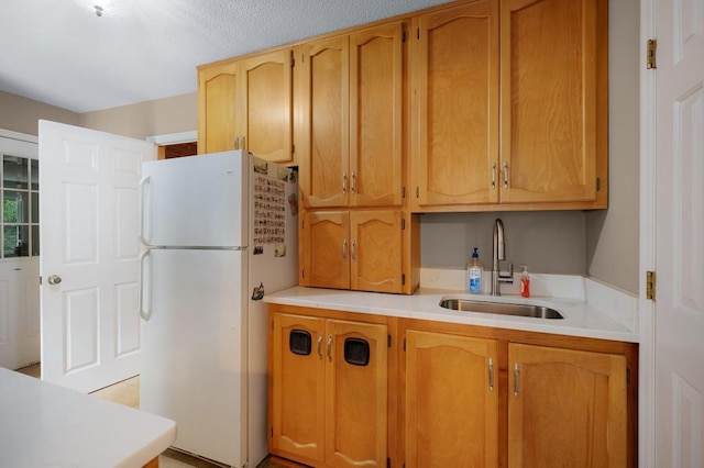 kitchen with a textured ceiling, sink, and white fridge