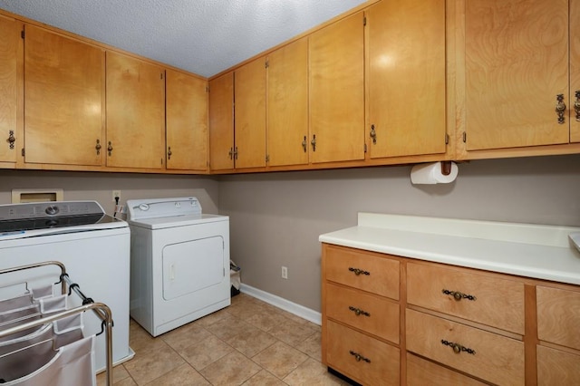 washroom with a textured ceiling, separate washer and dryer, light tile patterned floors, and cabinets