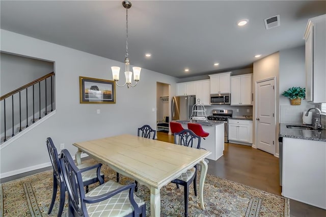 dining space featuring dark wood finished floors, a notable chandelier, recessed lighting, visible vents, and stairs