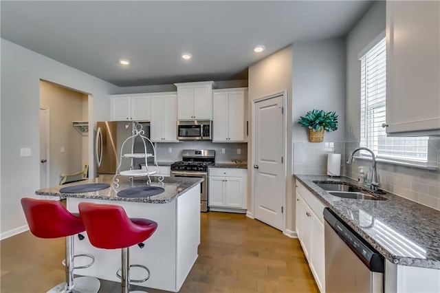 kitchen with appliances with stainless steel finishes, a sink, white cabinetry, and tasteful backsplash