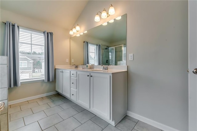 bathroom with tile patterned flooring, a sink, vaulted ceiling, double vanity, and a stall shower