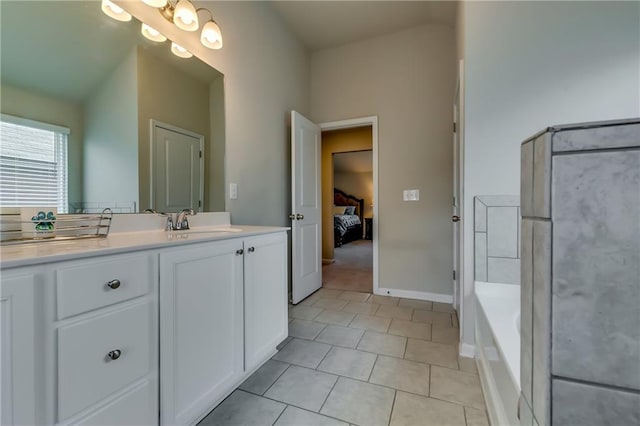 ensuite bathroom featuring ensuite bathroom, a bathing tub, vanity, baseboards, and tile patterned floors