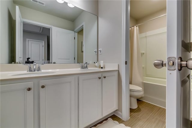 full bathroom with visible vents, a sink, toilet, and double vanity