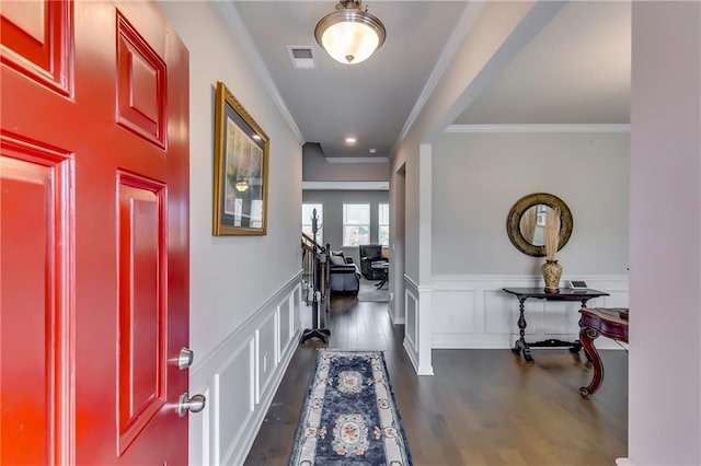 foyer with a wainscoted wall, visible vents, a decorative wall, dark wood-type flooring, and ornamental molding