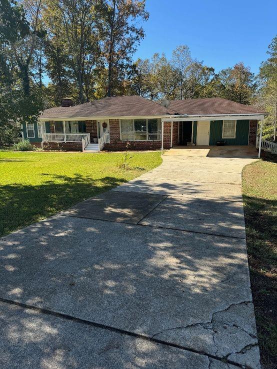 ranch-style home with a front lawn, a porch, and a carport