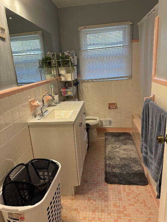 bathroom with vanity, toilet, and tile walls