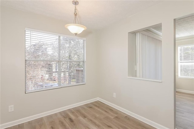 spare room featuring a textured ceiling and light hardwood / wood-style floors