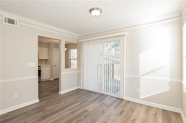 empty room with ornamental molding, light hardwood / wood-style floors, and a textured ceiling